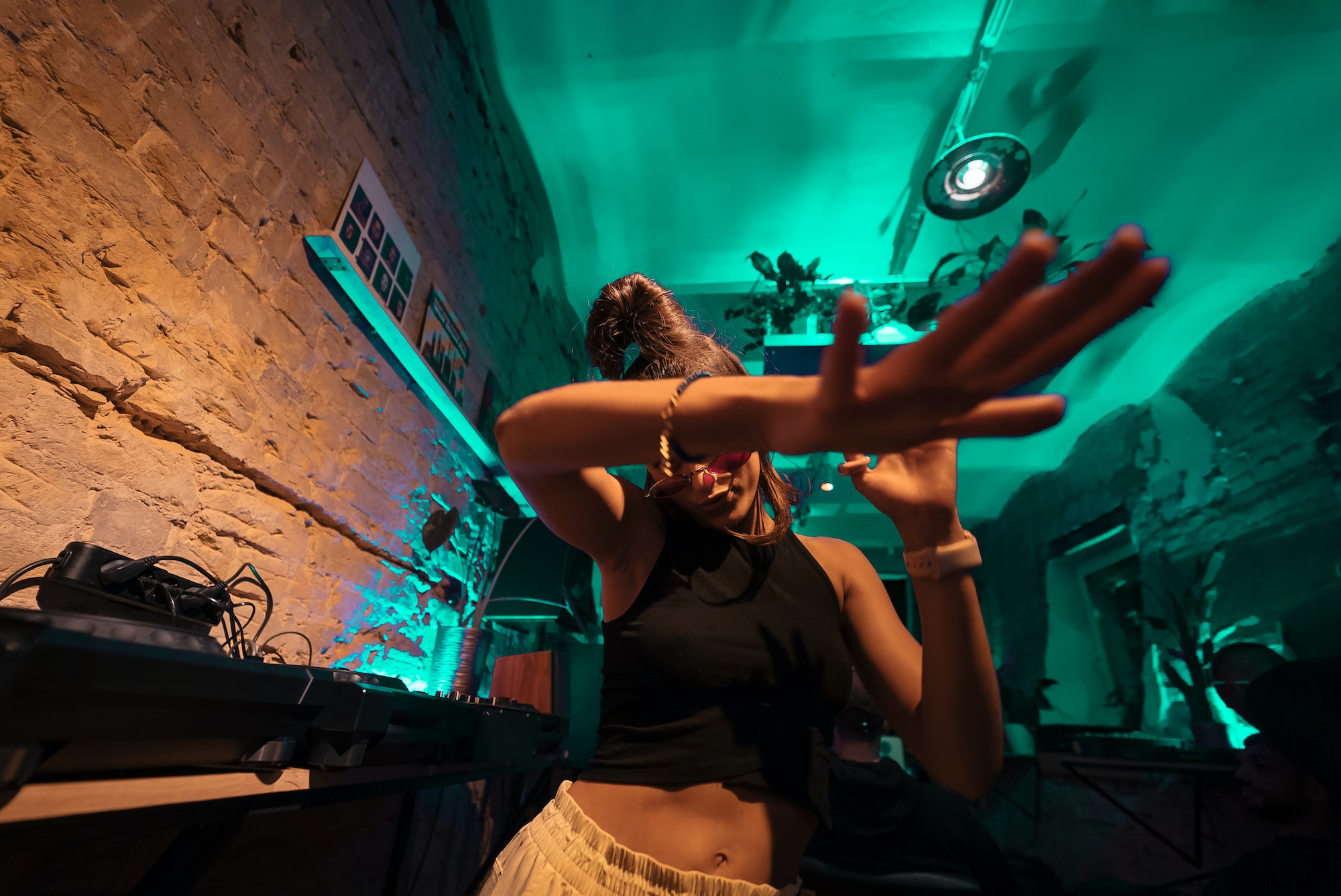 Beautiful female DJ dancing to techno in a small club