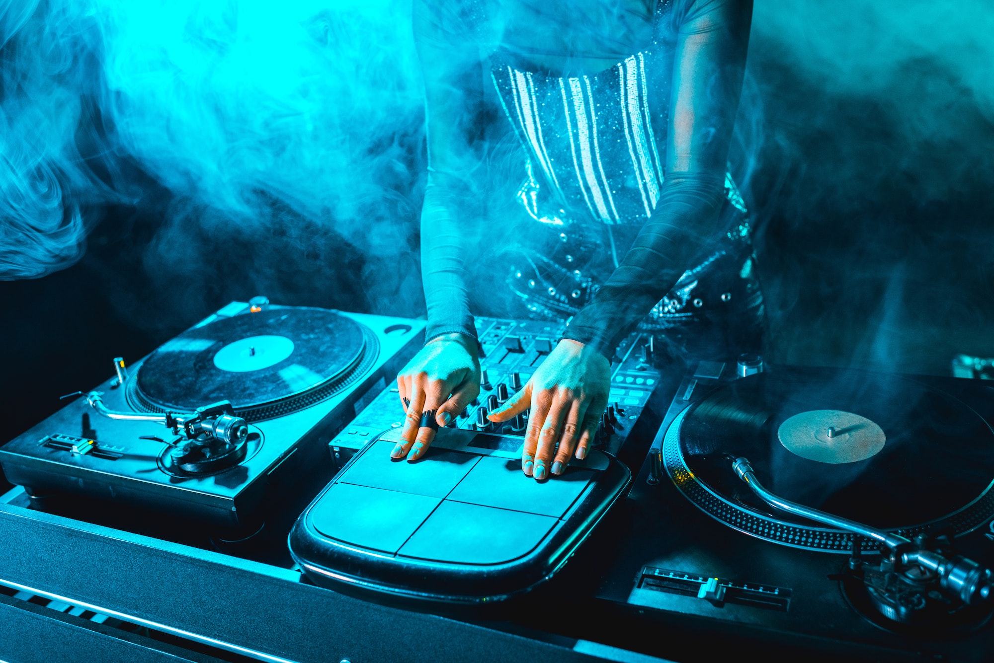 cropped view of dj woman using dj equipment in nightclub with smoke